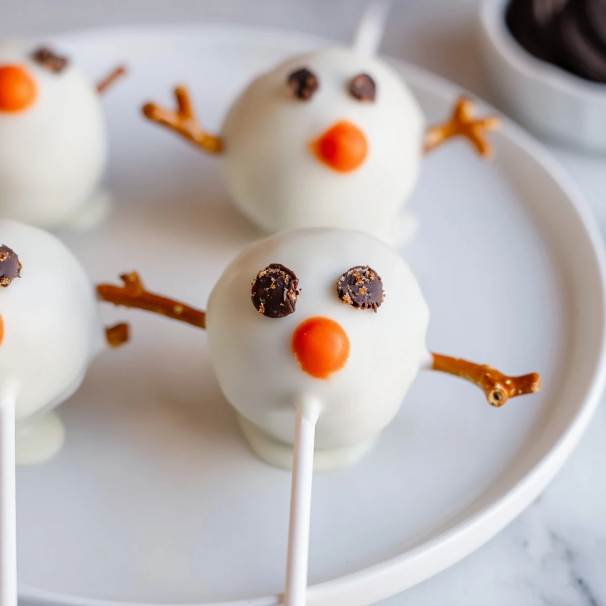 Festive Oreo Snowman Cake Pops with mini chocolate chip eyes, a perfect dessert recipe.