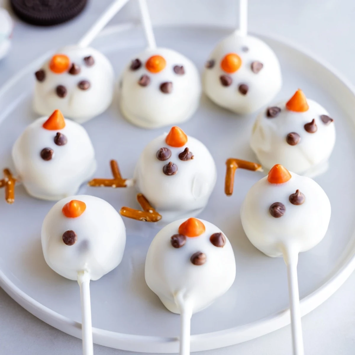 Homemade Oreo Snowman Cake Pops, a delicious and fun dessert with pretzel arms.