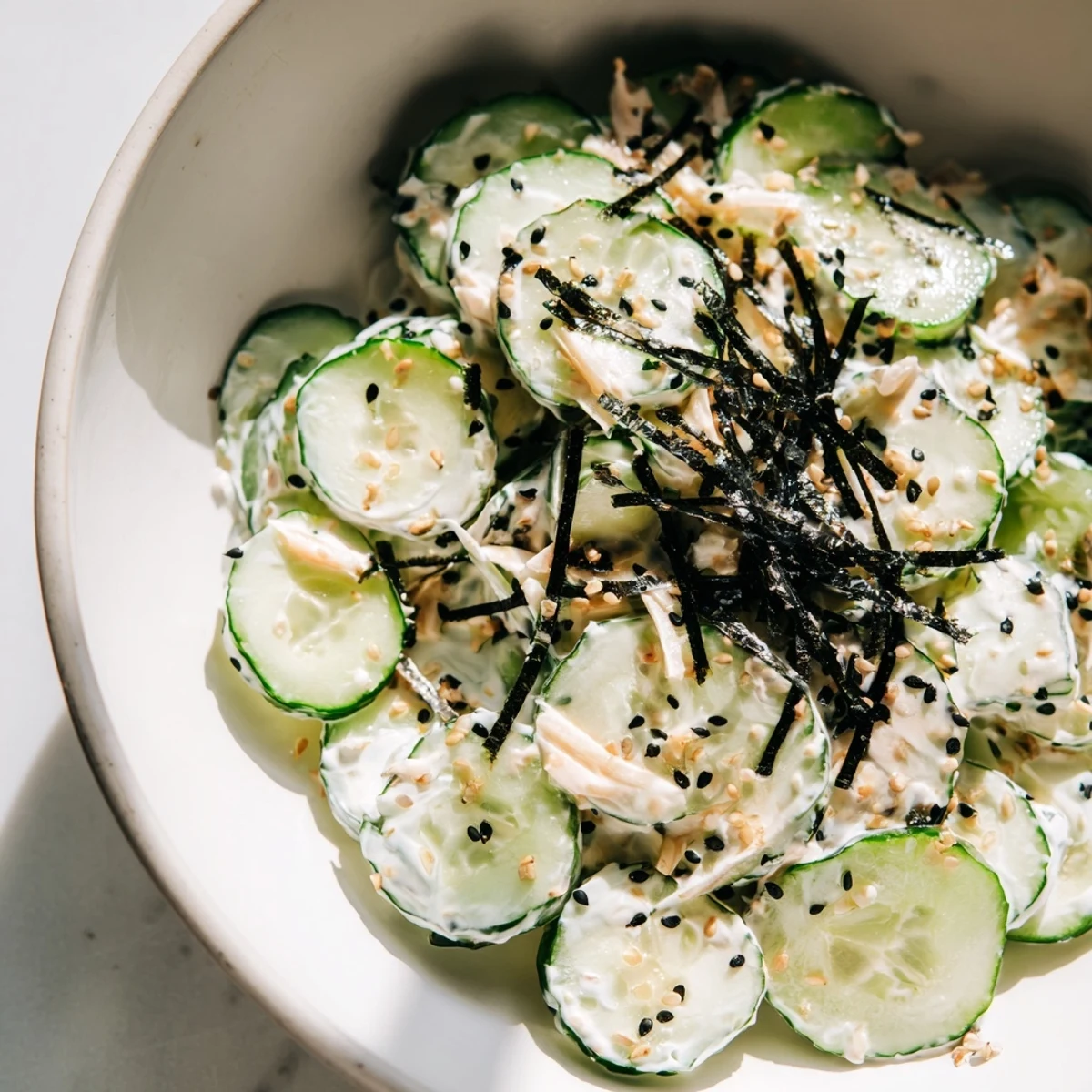 California Roll Cucumber Salad features crisp sliced cucumbers tossed with shredded imitation crab in a creamy sesame-mayo dressing.  