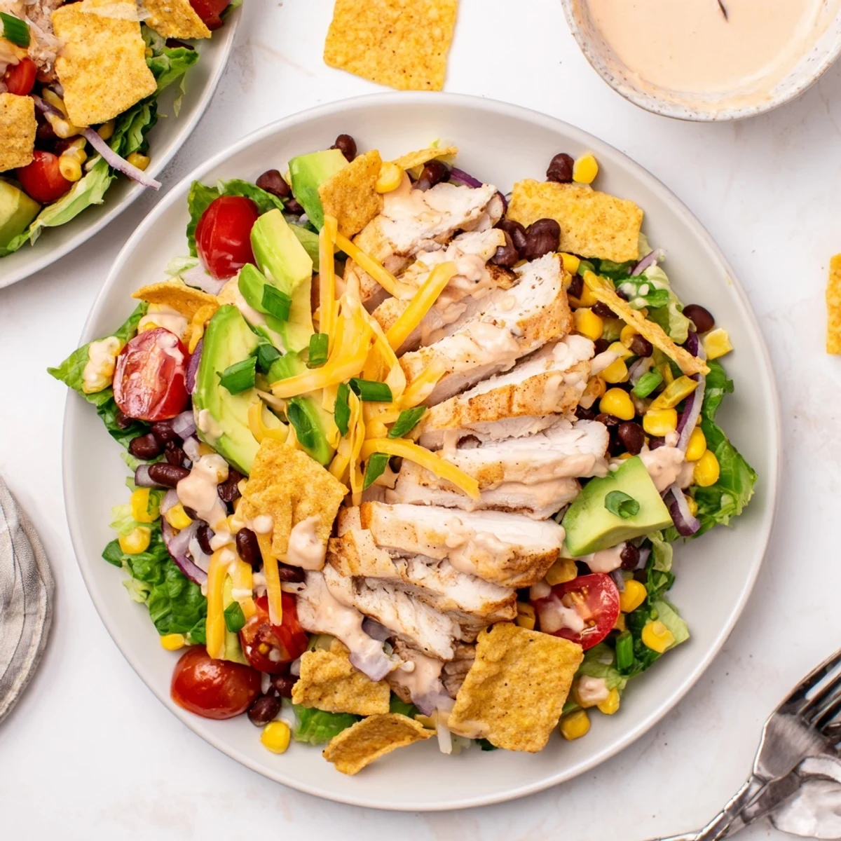 A hearty Crunchy Taco Chicken Salad arranged on a plate, mixing seasoned chicken with beans, corn, and fresh avocado for a Tex-Mex inspired meal.