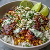 Street Corn Chicken and Rice Bowls served in white bowls with fresh cilantro, lime wedges, and a drizzle of spicy crema, ready for dinner.