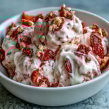 A close-up shows a Strawberry & Banana Yoghurt Cluster half-bitten, revealing a marbled swirl and crunchy banana chips for a satisfying frozen snack.