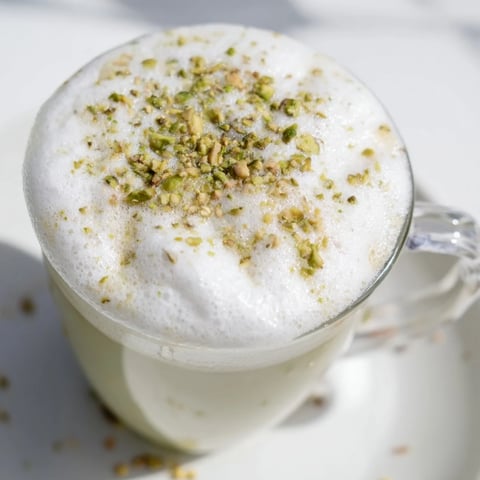 Steaming pistachio latte, crowned with fluffy cold foam, a perfect cafe-style drink to savor.