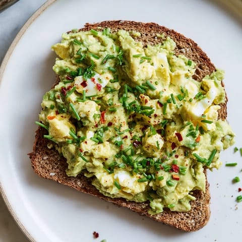 Freshly prepared Avocado Egg Smash, featuring vibrant herbs and a squeeze of zesty lemon.