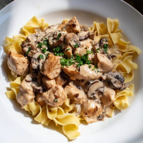 A top-down shot of Creamy Mushroom Chicken Pasta, garnished with parsley, looks so delicious.