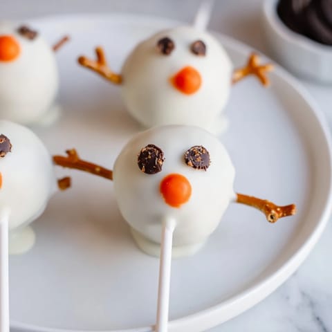 Festive Oreo Snowman Cake Pops with mini chocolate chip eyes, a perfect dessert recipe.