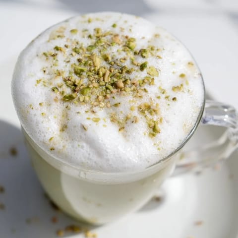 Steaming pistachio latte, crowned with fluffy cold foam, a perfect cafe-style drink to savor.