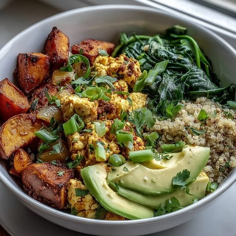 Savory vegan breakfast bowl featuring scrambled tofu, fluffy quinoa, and sweet roasted sweet potatoes topped with avocado.