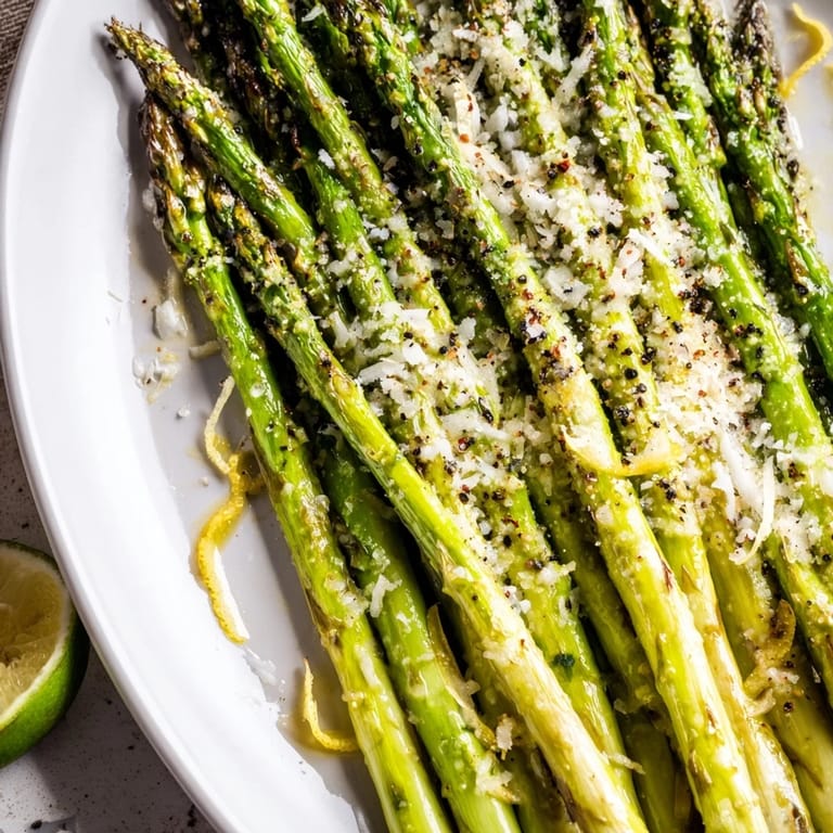 A vibrant close-up of roasted asparagus topped with fresh Parmesan and a squeeze of lemon.