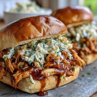 Juicy pulled BBQ chicken sandwiches with tangy coleslaw piled high on toasted brioche buns.